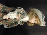 a doll that is wearing a green dress and hat