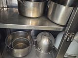 pots and pans sit on a metal shelf in a kitchen