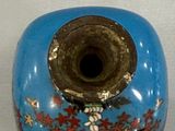 a blue vase with red and white flowers on it