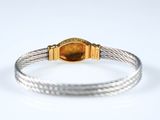 a close up of a gold and silver bracelet on a white surface