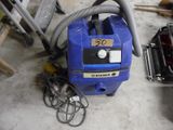 un aspirateur bleu posé par terre à côté d'un tas d'outils