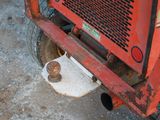 a close up of a red tractor with a rusted tire