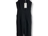the black jumpsuit is hanging on a hanger on a white wall