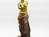 a bronze statue of a woman standing on a marble base
