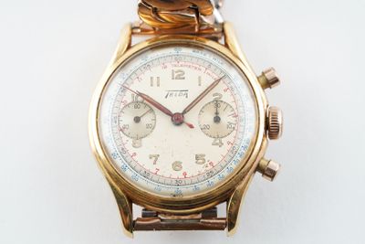 une montre en or entourée d'une chaîne sur une surface blanche