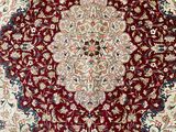 a close up of a red and white rug on a wooden floor