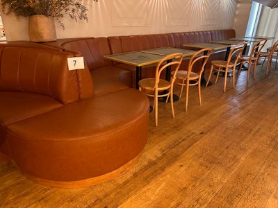 tables and chairs in a room with wood floors and a wall