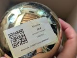 a person holding a gold ball with a qr code on it