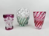 trois vases en verre de couleurs différentes posés l'un à côté de l'autre sur une surface blanche