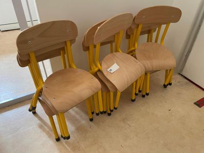 four wooden chairs that are lined up against the wall