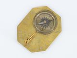 a gold clock with a compass on it on a white surface
