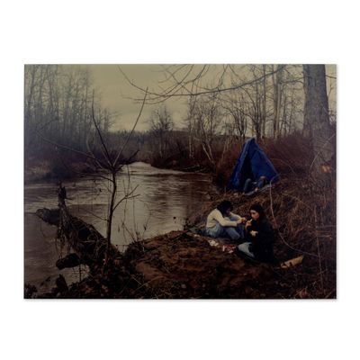 un homme assis au bord d'une rivière, à côté d'un parasol bleu