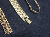a gold bracelet and a gold chain on a blue surface