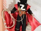 a black doll with a red cape and a cowboy hat