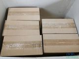 Plusieurs boîtes sont empilées dans un carton posé sur une surface blanche