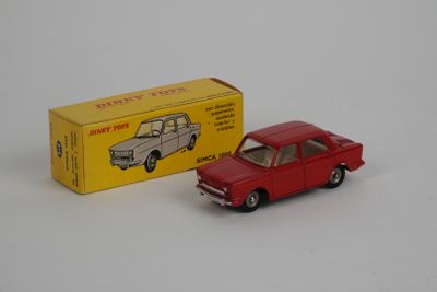 une petite voiture rouge à côté d'une boîte jaune sur une surface blanche