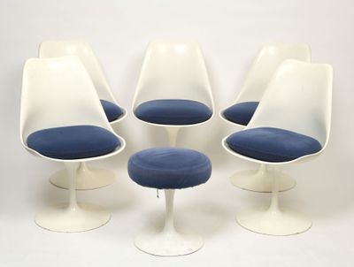 four white tulip chairs with blue cushions and a white stool