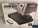 une boîte sur laquelle est posé un Game Boy, posée sur une table