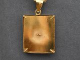 a close up of a gold plated pendant on a black surface