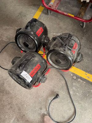 trois ventilateurs posés par terre près des pieds d'une personne