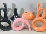 quatre vases de couleurs différentes et une paire de ciseaux sur la table