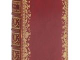 un vieux livre à la couverture rouge posé sur une surface blanche