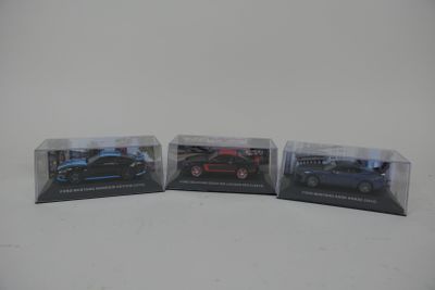 trois petites voitures sont posées dans une vitrine, sur une surface blanche