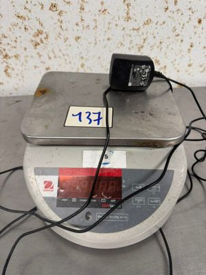 une petite balance électronique surmontée d'un chargeur