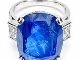 a close up of a blue sapphire and diamond ring on a white background