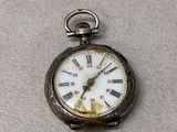 a silver pocket watch with roman numerals on it