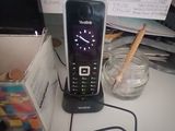 a cell phone sitting on a desk next to a cup of water