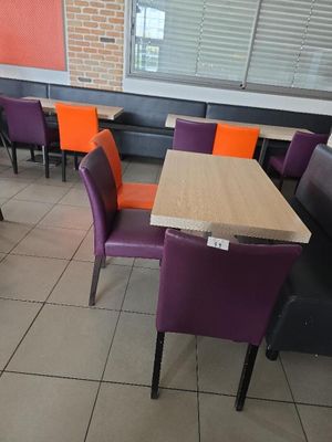des chaises et des tables violettes et orange dans un restaurant aux murs en briques
