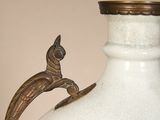 a white vase with a bird on top of it