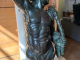 bronze statue of a man holding a basketball ball in his right hand