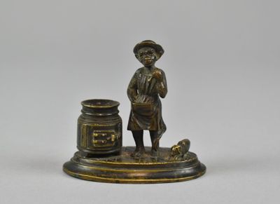 an antique bronze figurine of a boy with a jar of honey