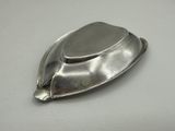 a silver plate with a lid on a white surface