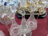de nombreux objets en verre posés sur une table, avec une horloge en arrière-plan