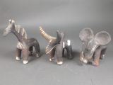 trois figurines d'éléphants et une girafe sur fond gris
