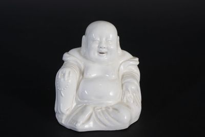 une petite statue de Bouddha blanche posée sur une surface noire