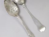 une paire de cuillères en argent posées sur une table blanche