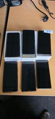 several cell phones are sitting on a table with a person standing next to them