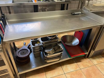 une table en acier inoxydable sur laquelle sont posés des casseroles et des poêles