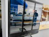 un homme debout dans une pièce dont la porte est en verre