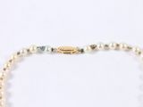 pearl necklace with a gold plated clasp and a green and white bead
