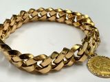 a close up of a gold bracelet with a coin on it