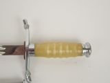 a sword with a yellow handle on a white surface