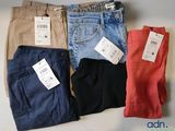 quatre paires de pantalons pour homme, encore étiquetés, posées sur une table