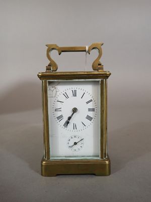 une petite horloge en laiton avec des chiffres romains sur le cadran