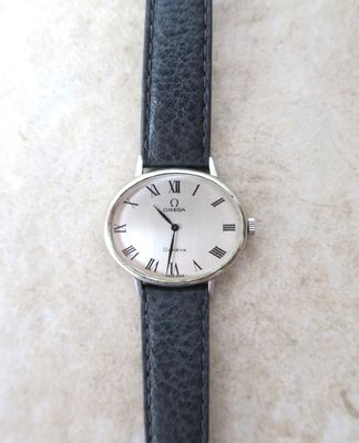 une montre en argent avec des chiffres romains, montée sur un bracelet en cuir noir
