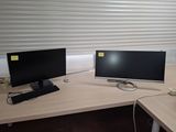 two computer monitors sitting on a desk in an office